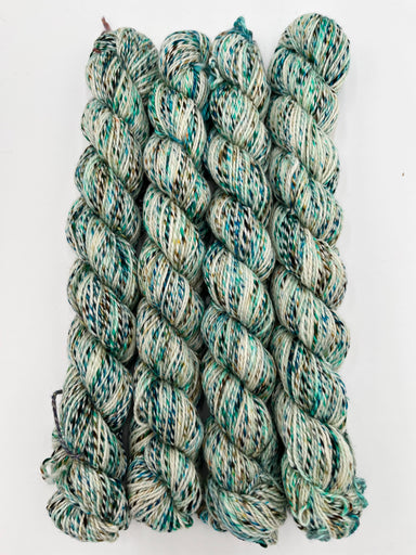 Four twisted skeins of variegated yarn with a marled pattern of teal, green, cream, and off-white, arranged vertically on a plain white background.